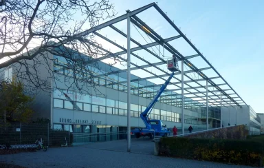 Moderne Gebäude mit Veranda und Bauarbeiter auf einem Kran.